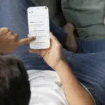 Férfi kanapén, okostelefonon megnyitott szerzi applikációval