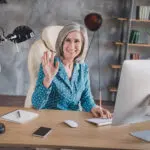 Íróasztal mögött ülő integető nő, bemutatkozás